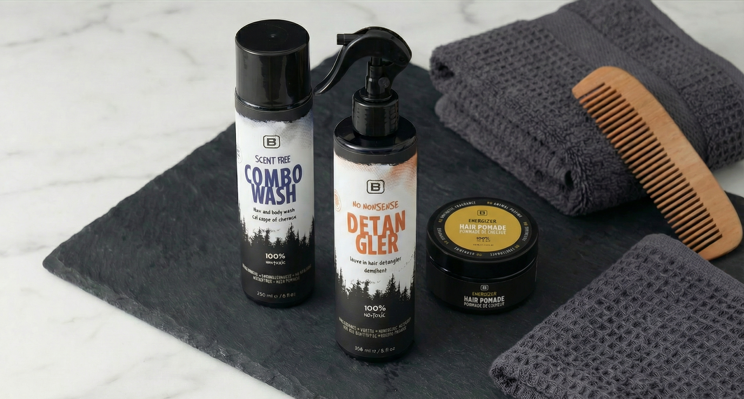 Set of grooming products including a bottle, a jar, and a comb on a dark mat with a towel.